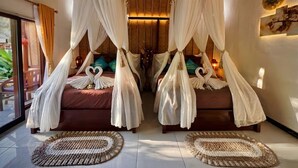 Une chambre avec deux lits, chacun doté d’un baldaquin, d’une grande fenêtre et d’une vue sur la verdure environnante.