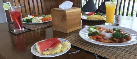 A table with a meal, a drink, and a tissue box at Meket Bungalows.