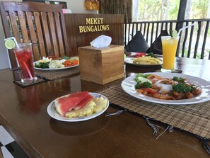 Una mesa con comida, una bebida y una caja de pañuelos en Meket Bungalows.