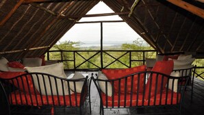 A room with a high ceiling and a large window, offering a view of the outdoors. - Ol Loika Cottage (Naivasha)