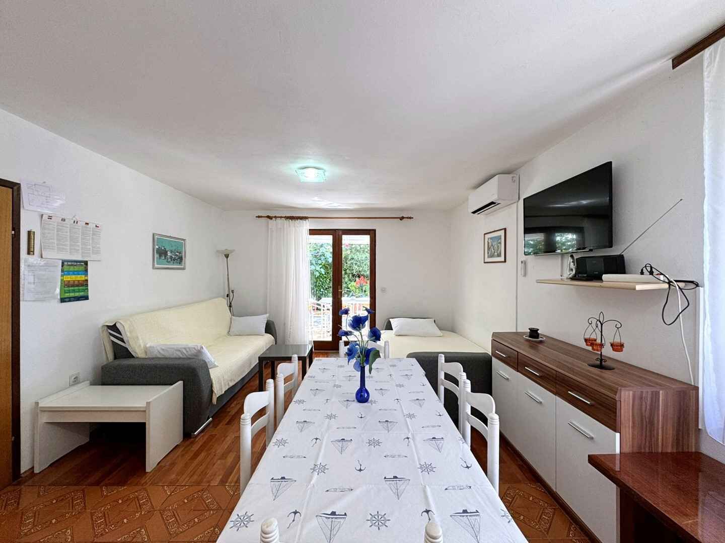 Un espace de vie compact comprenant un canapé, une table à manger, un coin cuisine et un téléviseur.