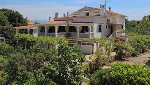 A two-story house with a tiled roof, surrounded by greenery and trees. - Holiday apartment mit Terrasse und Klimaanlage (Šilo)