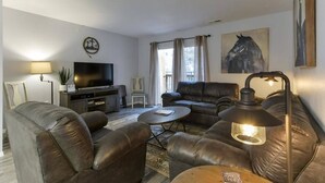 A living room with leather sofas, a coffee table, a TV, and a lamp. - Western Comfort (Branson)