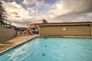 A swimming pool with a wooden fence, lounge chairs, and a covered area. - Western Comfort (Branson)