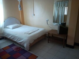 A simple, clean room with a bed, a desk, and a chair.
