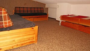 A small, compact room with two wooden beds, one with a plaid blanket and the other with a plain cover. - Studio 6 pers avec mezzanine, accès pistes, proche commerces, balcon Est (Les Orres)