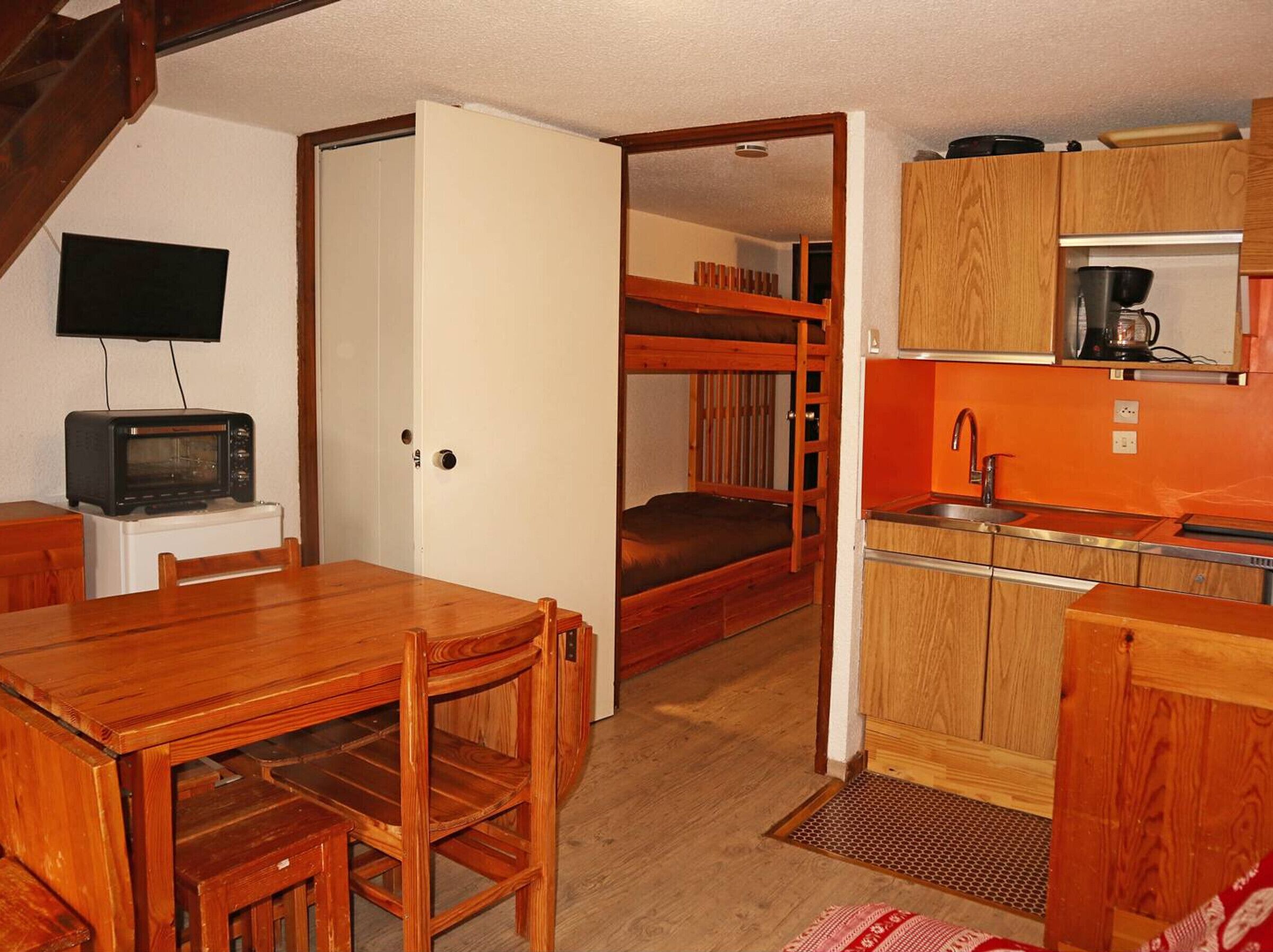 Una cocina compacta con armarios de madera, un microondas integrado y un lavamanos pequeño.