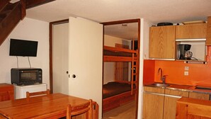 A compact kitchen with wooden cabinets, a built-in microwave, and a small sink. - Studio 6 pers avec mezzanine, accès pistes, proche commerces, balcon Est (Les Orres)