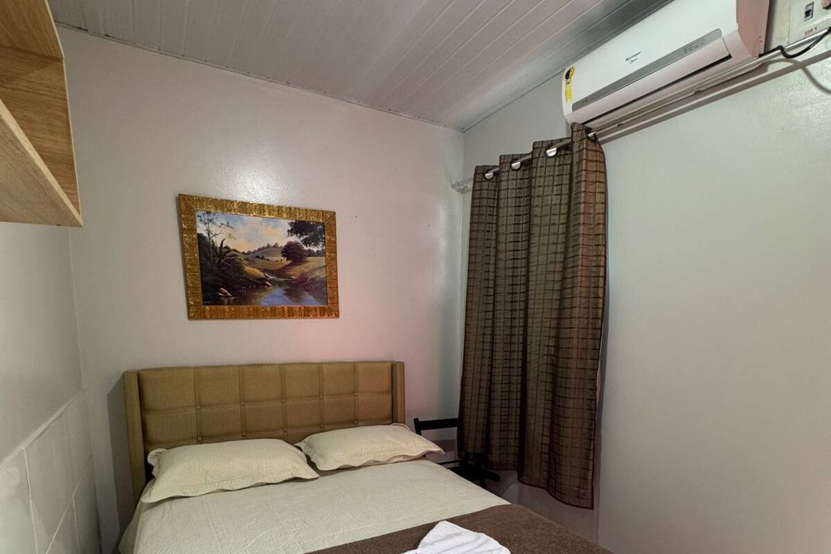 Un lit bien fait, avec une couverture marron et une serviette blanche pliée posée sur le dessus.