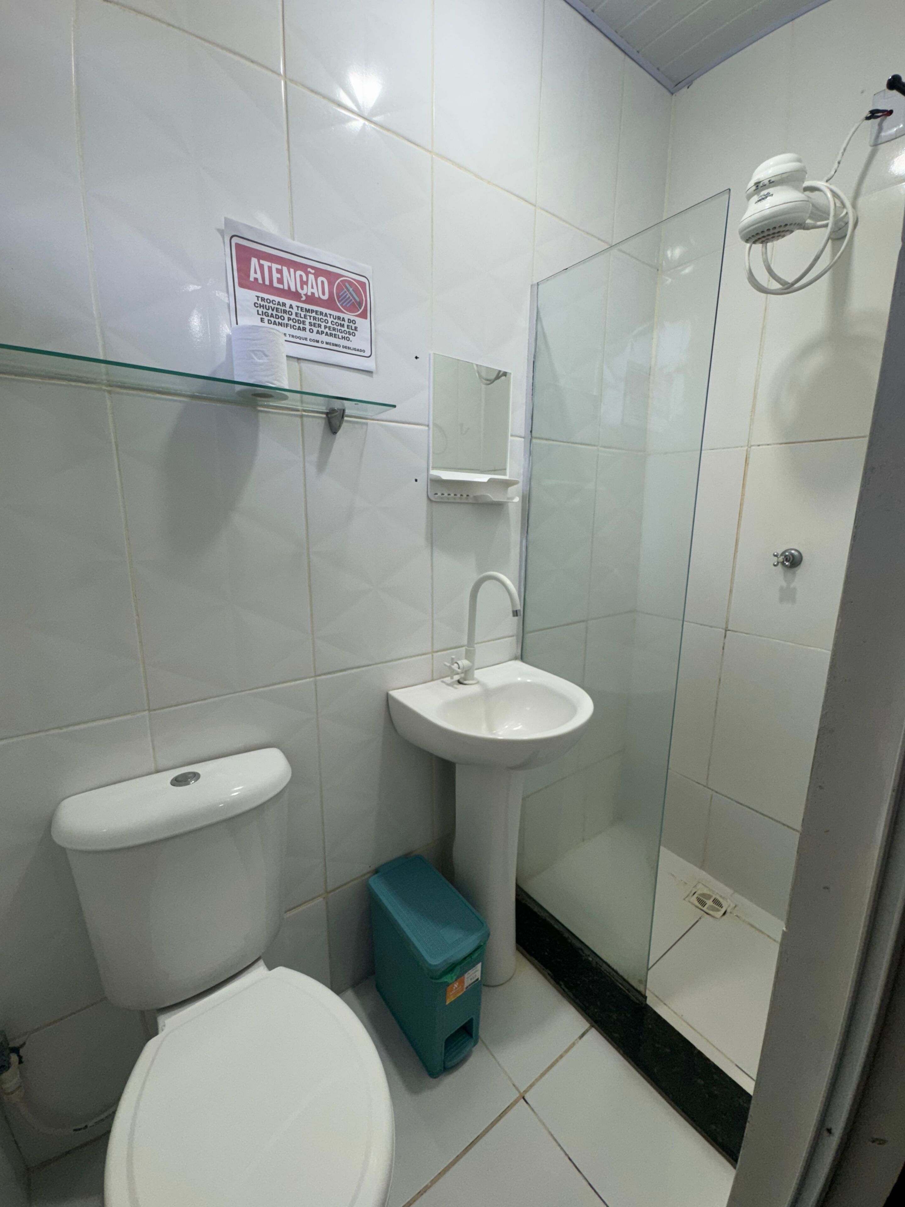 A bathroom with a toilet, sink, and glass shower enclosure.