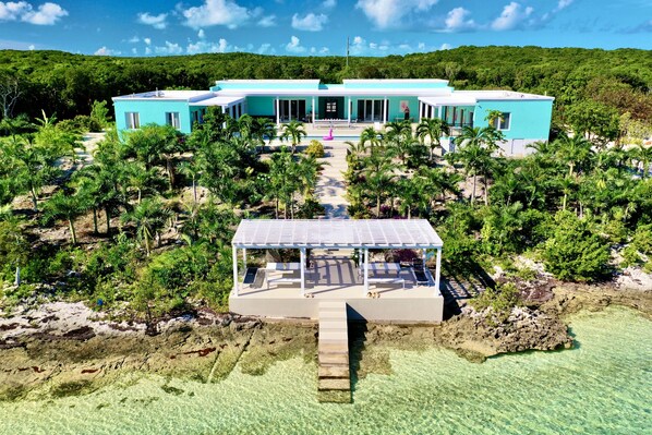 A resort with a central building, a covered pool area, and a clear view of the surrounding tropical landscape.
