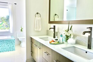 A modern bathroom with two sinks, a toilet, and a bathtub.
