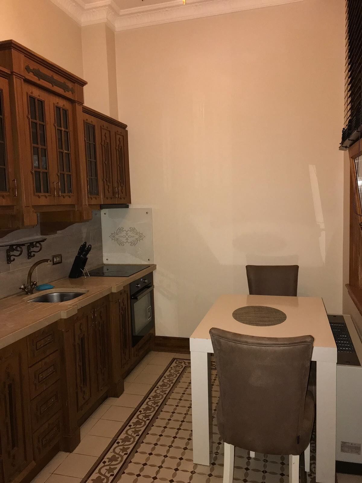 A compact kitchen with wooden cabinets, a sink, a stove, and a dining area with a table and chairs.
