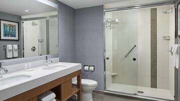 A modern bathroom with dual sinks, a toilet, and a glass-enclosed shower.