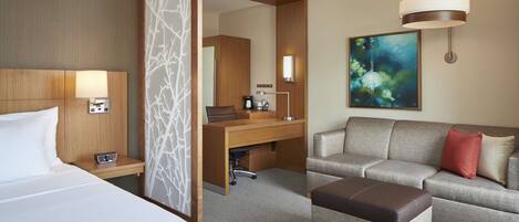 A hotel room with a bed, a desk, a sofa, and a coffee table.