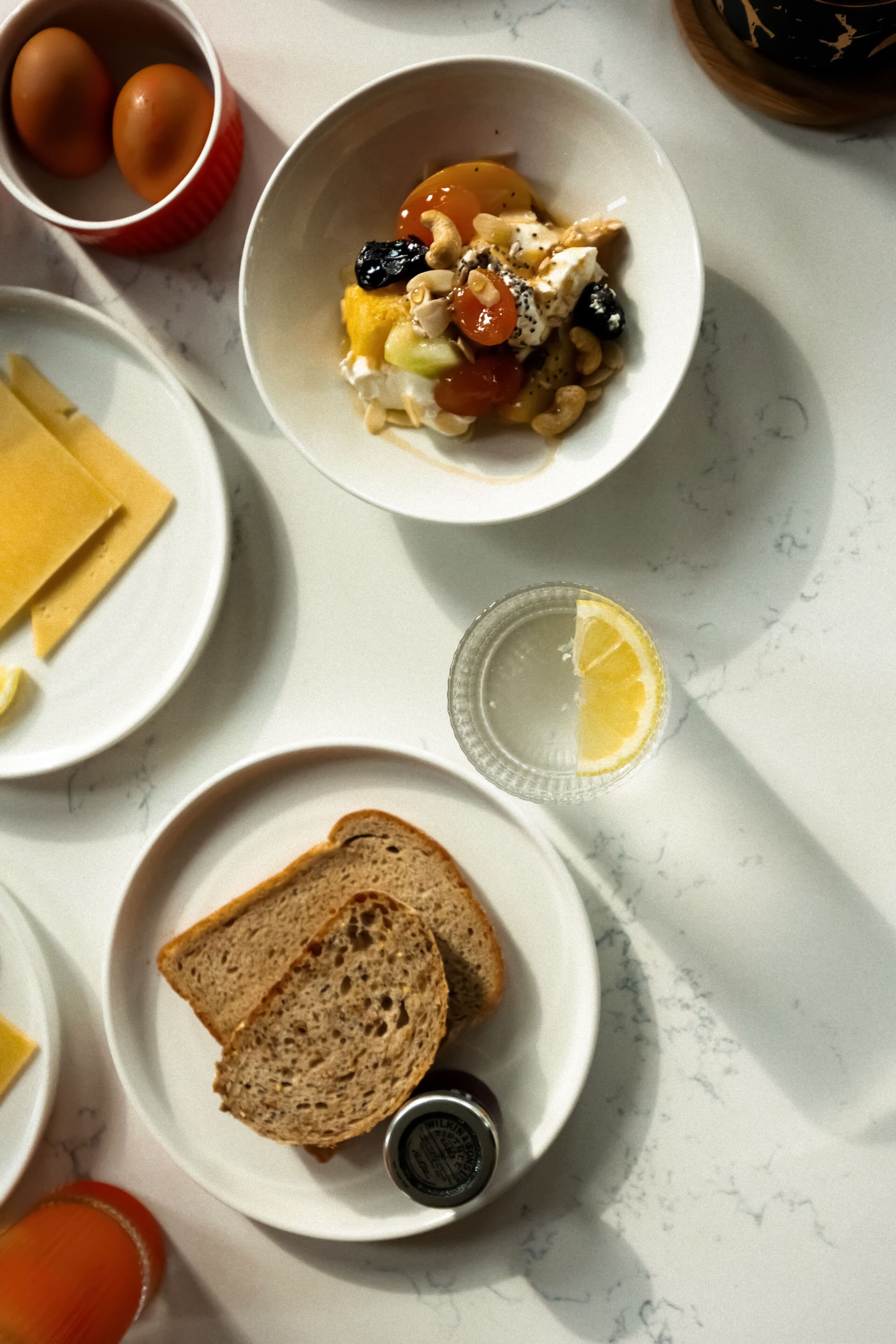 Une table en marbre dressée pour le petit-déjeuner, avec un bol de céréales, des œufs et des toasts.