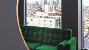 A room with a green sofa, a large window, and a view of a cityscape. - The Gate London City (London)