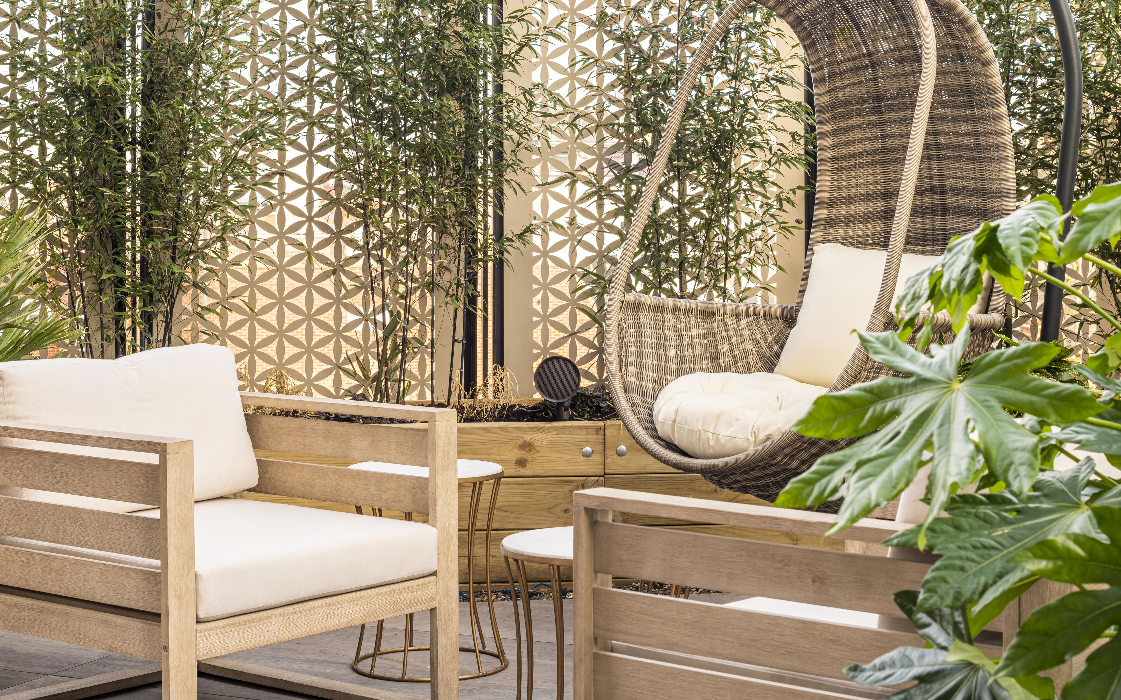 Zona relax esterna con sedute in legno, una sedia in vimini e una panca imbottita.