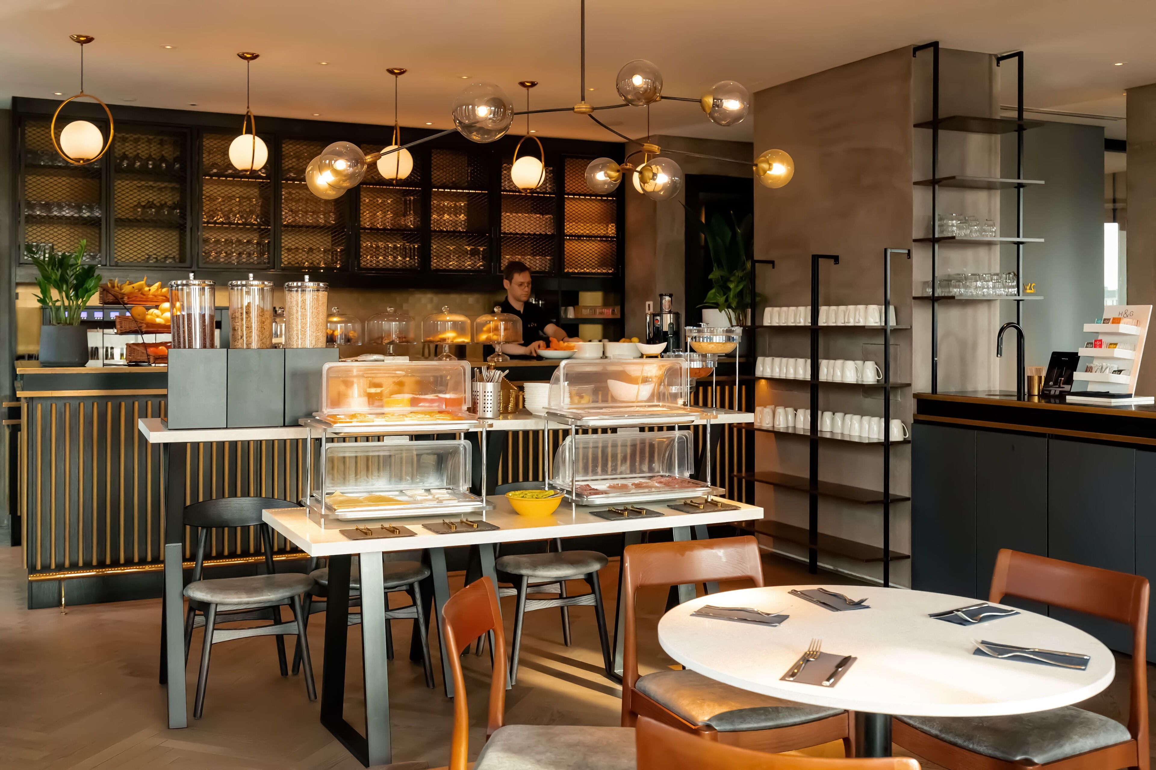 A modern cafe with a bar area, seating, and a chef preparing food.