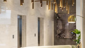 A modern lobby with a green sofa, a grey armchair, and a unique abstract wall art piece.