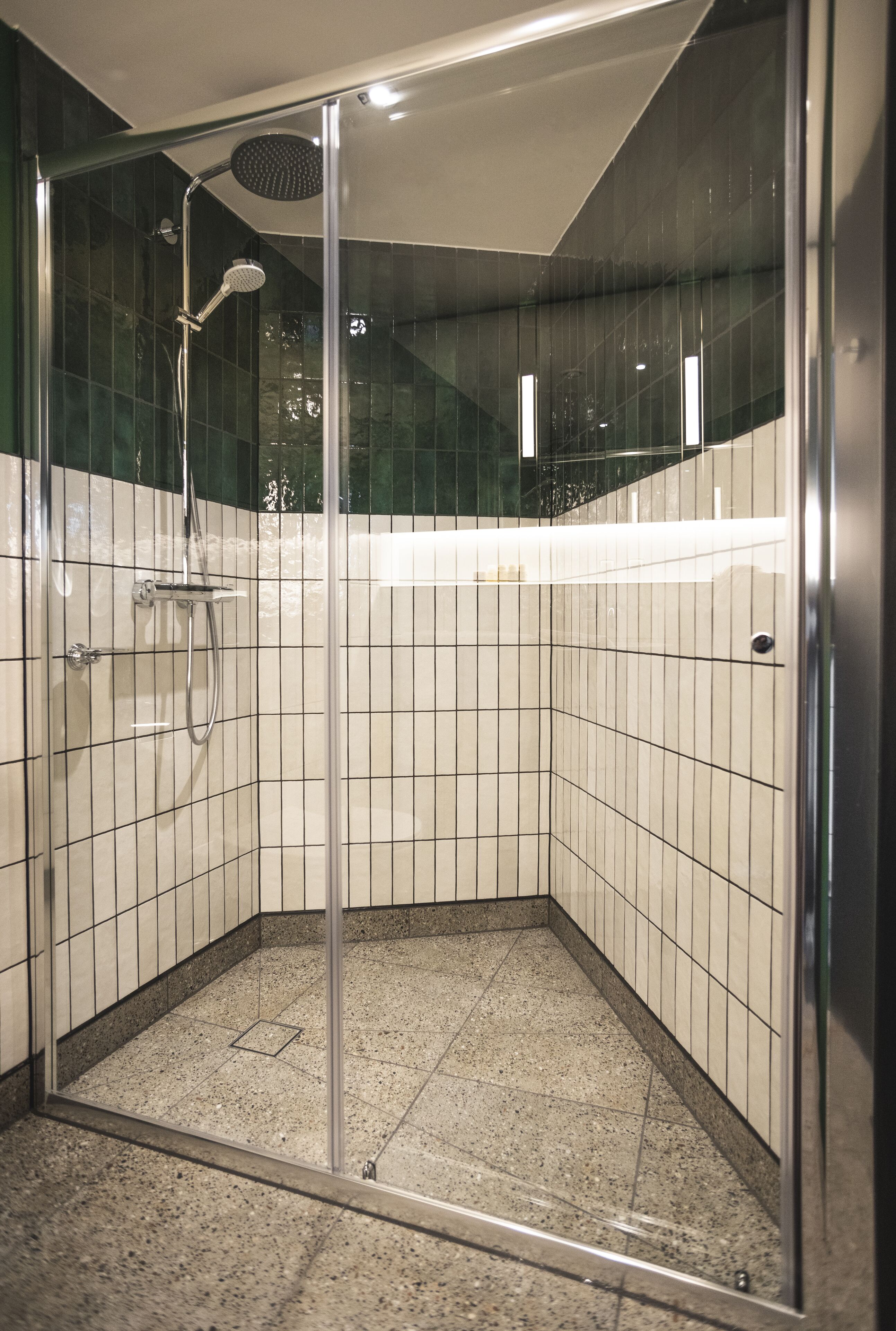 A glass-enclosed shower stall with a handheld showerhead and a wall-mounted faucet.