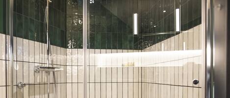 A glass-enclosed shower stall with a handheld showerhead and a wall-mounted faucet.