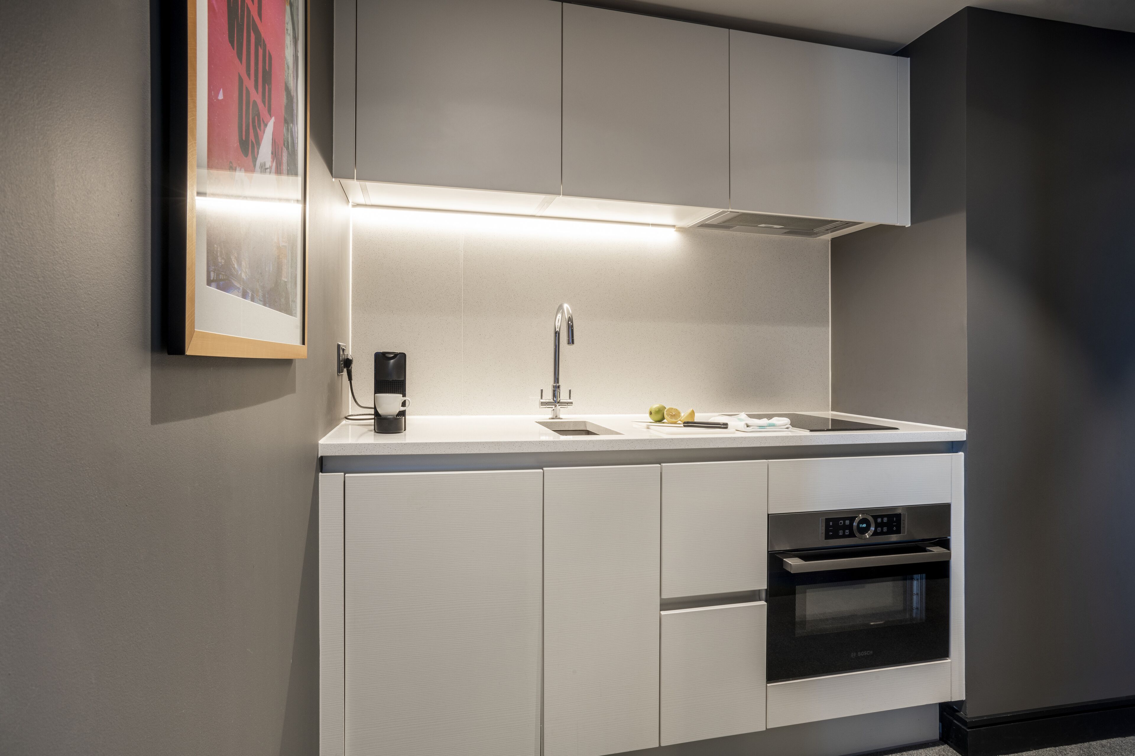 A modern kitchen with white cabinetry, a stainless steel sink, and a built-in oven.