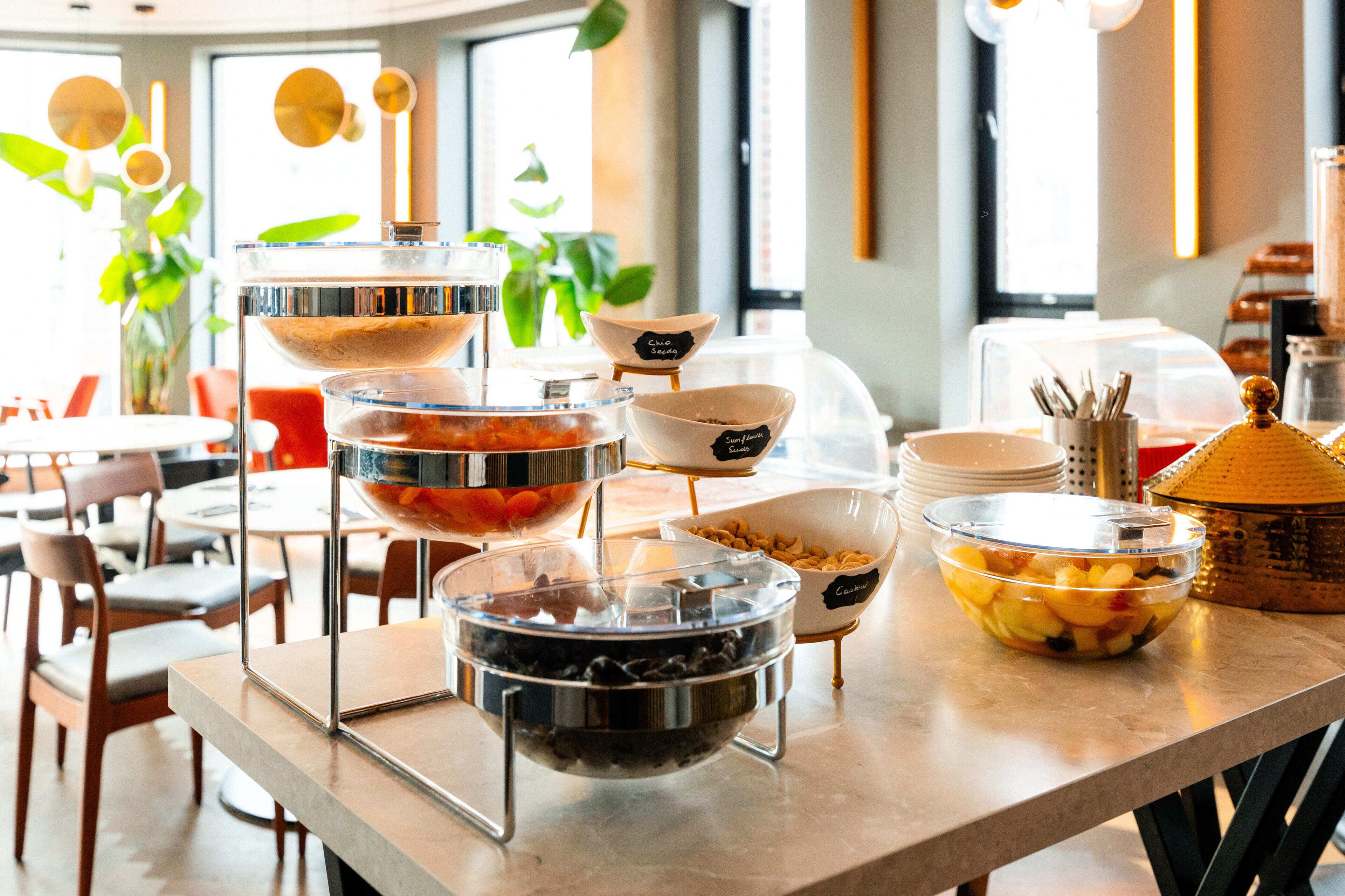 Ein Buffet mit verschiedenen Speisebehältern, beschriftet mit Bezeichnungen wie ‚Clover Seed‘ und ‚Sunflower‘.