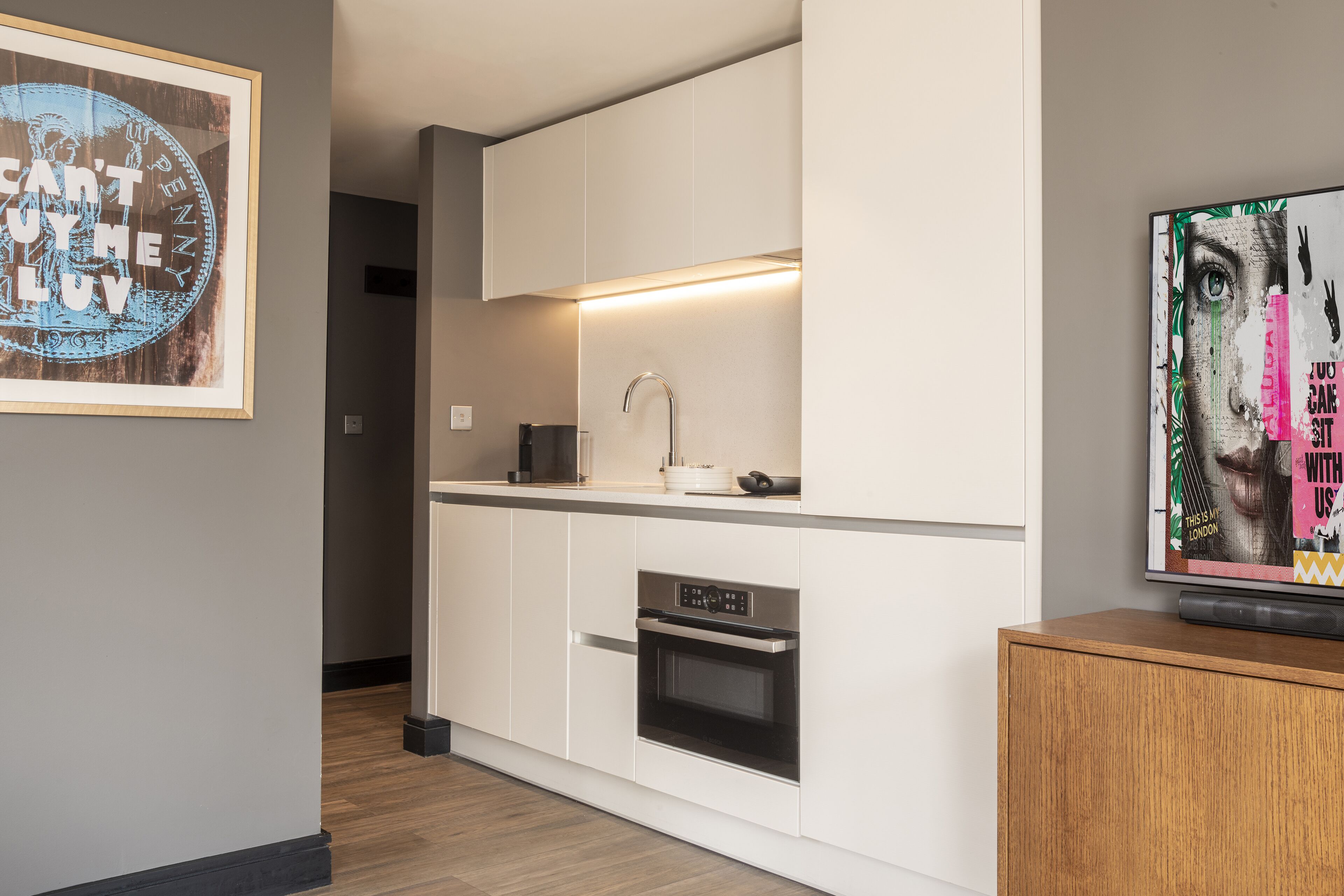 A modern kitchen with white cabinetry, a built-in oven, and a countertop with a sink.