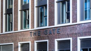 A building facade with the sign "THE GATE" and multiple windows with blinds.
