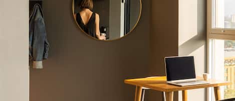 A modern room with a round mirror, a wooden table with a laptop, and a chair.