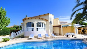 Ein Poolbereich mit Pool, Liegestühlen und einem Gebäude mit Balkon.