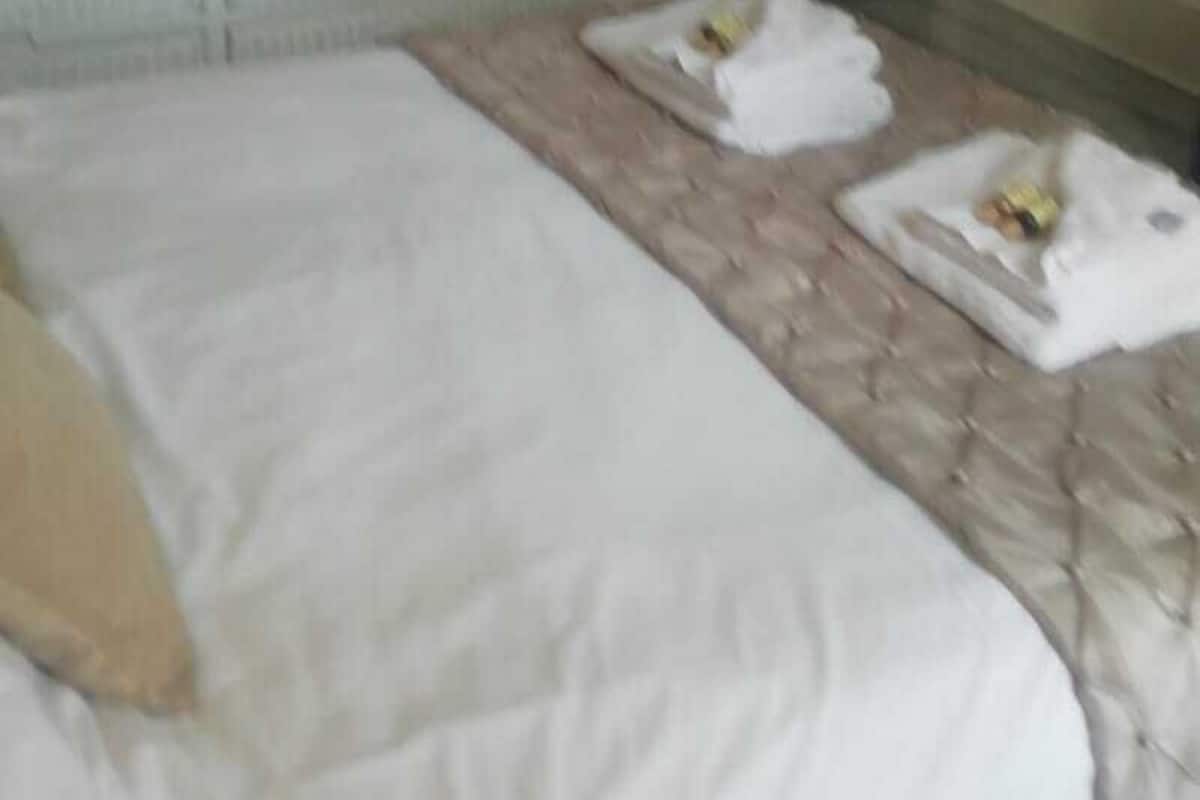 A hotel room with a bed, a flat-screen TV mounted on the wall, a door, and a radiator.