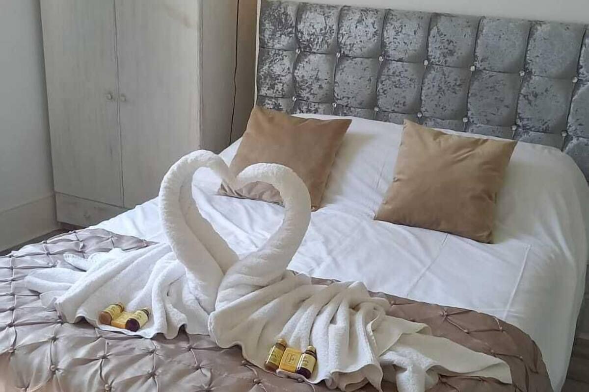 A neatly made bed with a tufted headboard, a bedside table with a lamp, and a wardrobe.