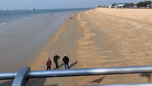 Uma praia com um corrimão de metal em primeiro plano.