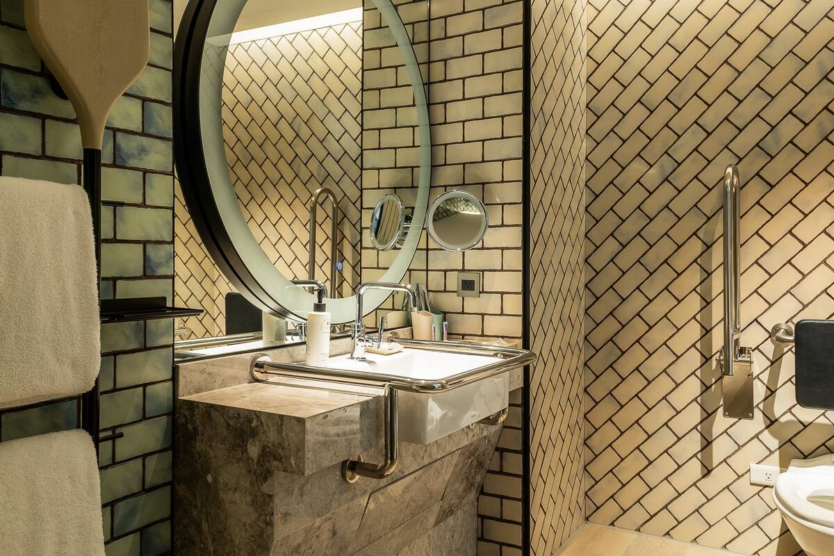A bathroom with a marble sink, a mirror, a toilet, and a towel rack.