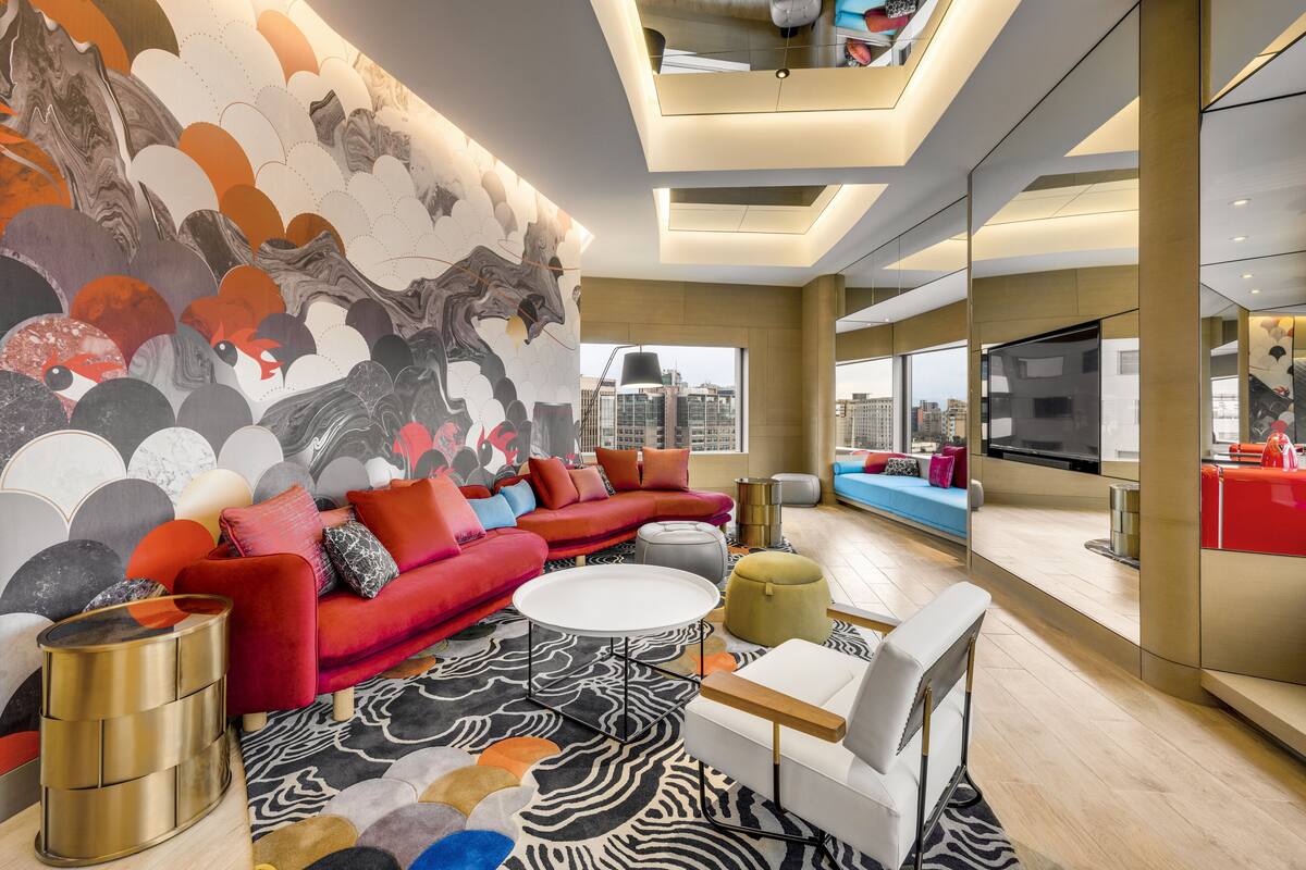 A modern living room with a red sofa, a white coffee table, and a large abstract mural on the wall.