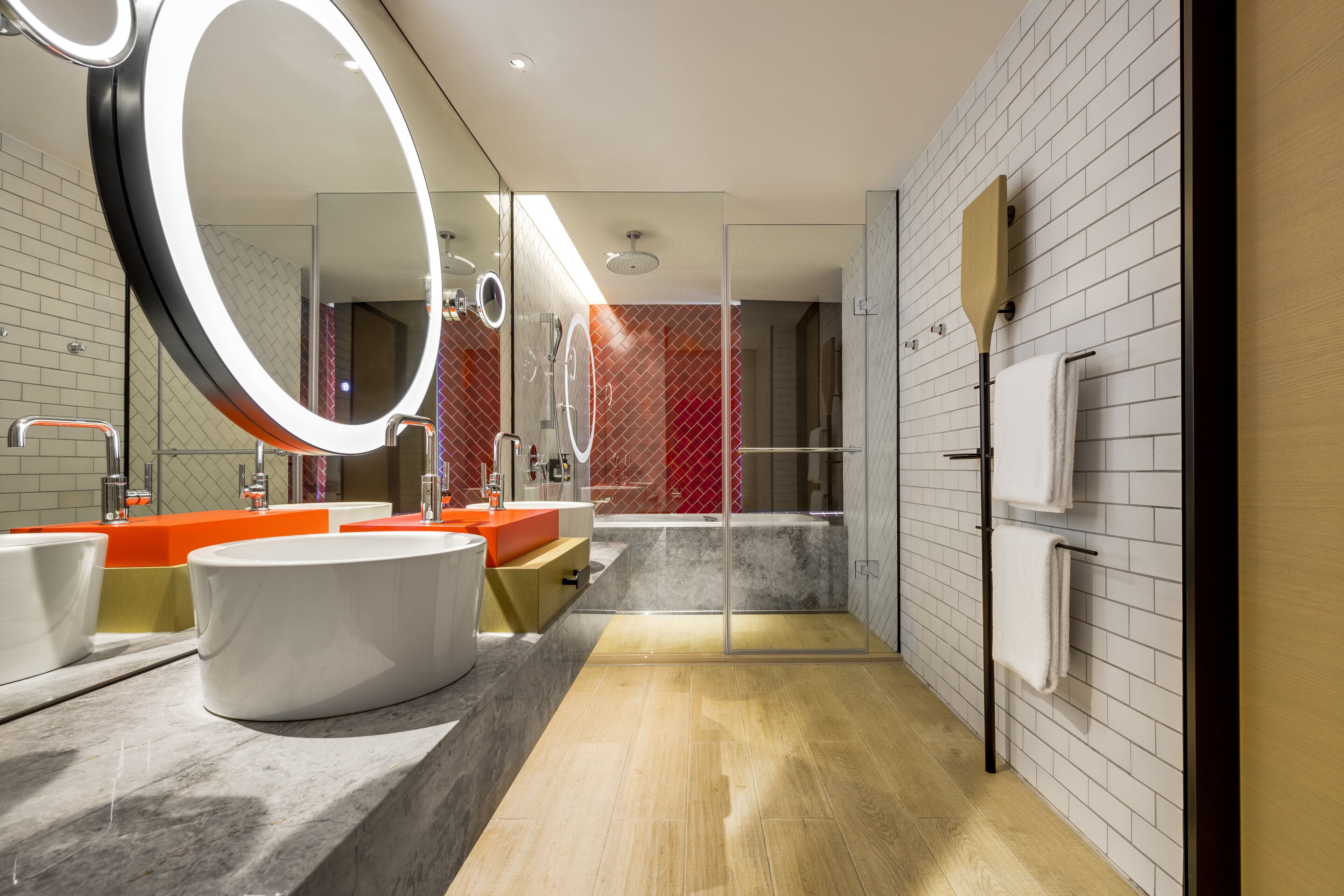 A modern bathroom with two sinks, a bathtub, a shower, and a glass-enclosed shower area.