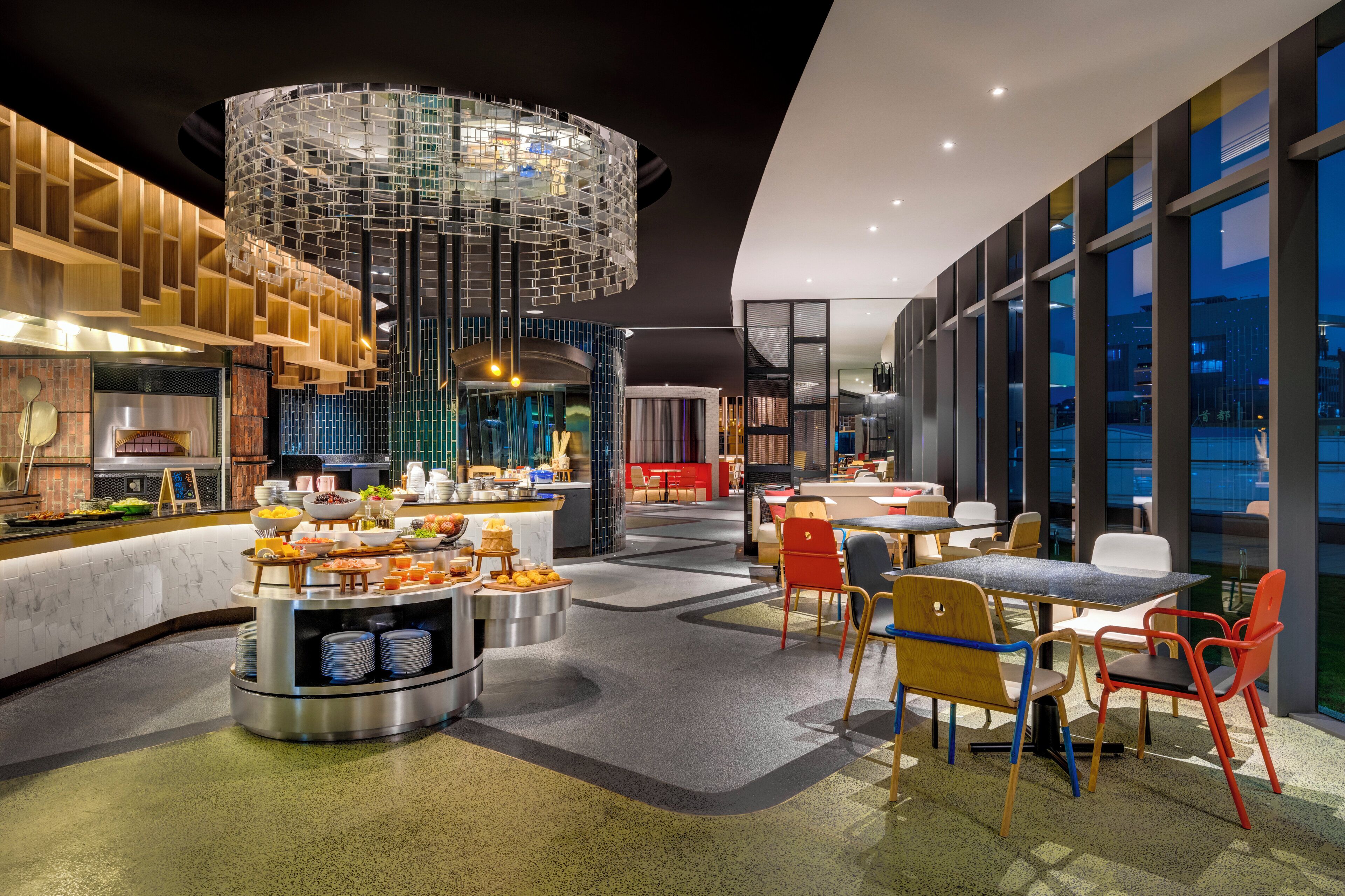 A modern restaurant interior with a central serving area, seating arrangements, and a distinctive ceiling design.