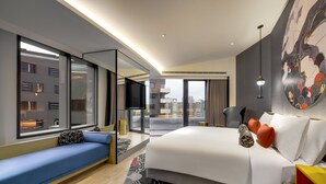 Une chambre d’hôtel moderne dotée d’un grand lit, d’un coin salon, d’une grande fenêtre et offrant une vue sur la ville.