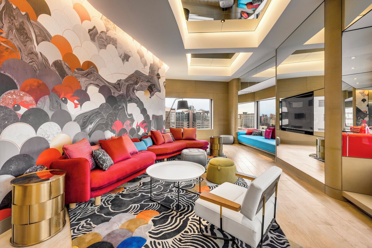 Ein modernes Wohnzimmer mit einem roten Sofa, einem weißen Couchtisch und einem großen, abstrakten Wandbild.