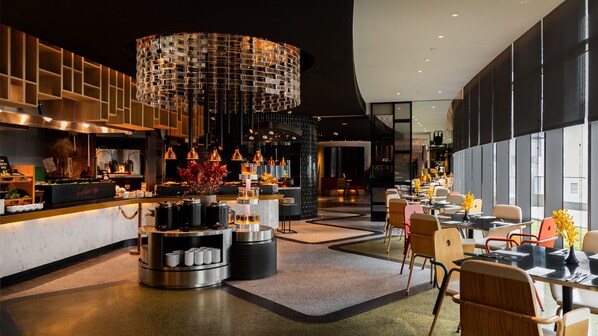 Un restaurant moderne doté d’un bar central, d’un espace repas aménagé et d’un luminaire suspendu original.