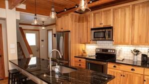 A modern kitchen with wooden cabinets, stainless steel appliances, and a granite countertop. - 1320 Tennis Townhome 3 Bedroom Townhouse by RedAwning (Keystone)