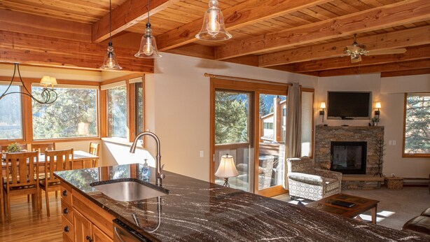 A spacious kitchen with a large island, wooden ceiling beams, and a stone fireplace. - 1320 Tennis Townhome 3 Bedroom Townhouse by RedAwning (Keystone)