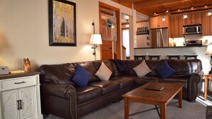 A living room with a brown leather sectional sofa, a wooden coffee table, and a white cabinet with a decorative owl. - 1320 Tennis Townhome 3 Bedroom Townhouse by RedAwning (Keystone)
