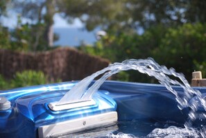 A hot tub with water flowing out of a spout, surrounded by greenery. - La Calanque du Boucharel (Fréjus)