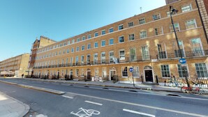 A multi-story brick building with a row of windows and a bicycle lane on the street in front. - Two bedroom apartment with sofa bed (London)