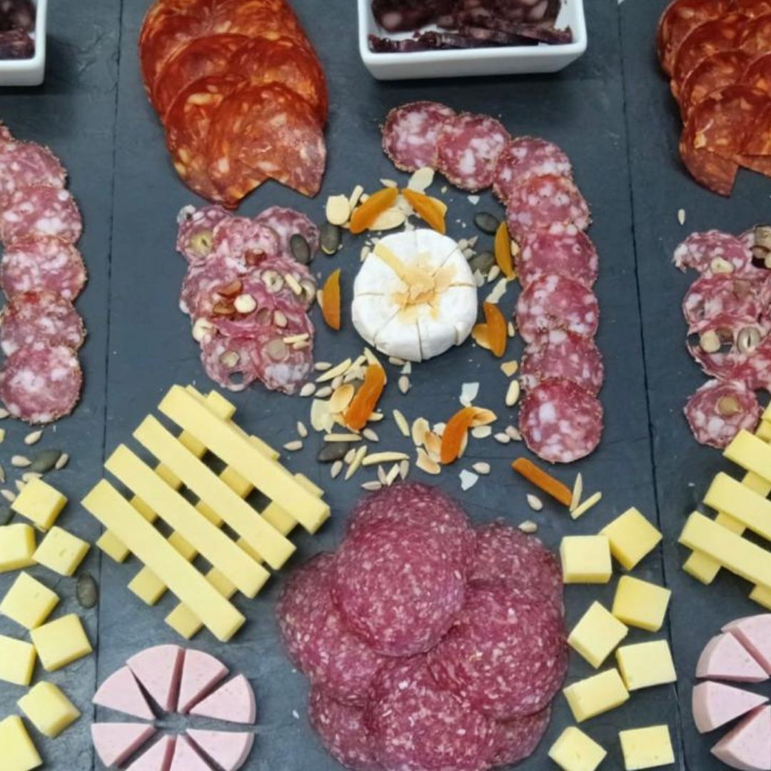 Une sélection de charcuteries et de fromages, présentés sur une planche d’ardoise.