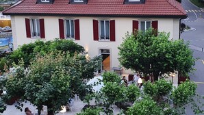 A two-story building with a red-tiled roof, dormer windows, and red shutters. - Hotel La Belle Croix (Romont)