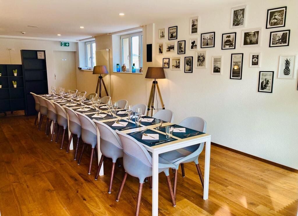 Un coin repas avec une longue table dressée pour le repas, des chaises, une lampe et des tableaux encadrés accrochés au mur.
